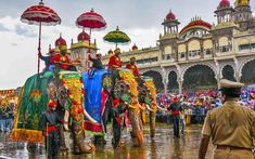 people are riding elephants in the rain with umbrellas on their heads and wearing costumes