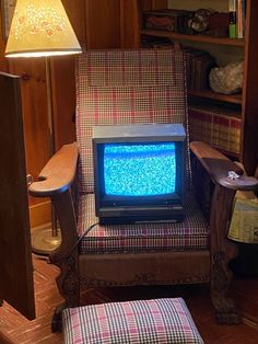 an old fashioned television sitting on top of a chair in a living room next to a lamp