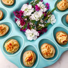 an arrangement of baked goods on a blue tray with flowers in the middle and purple, white, and red colors