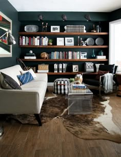 a living room filled with furniture and bookshelves next to a wall mounted book shelf