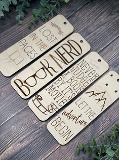 three wooden tags with words on them sitting on top of a wood floor next to plants