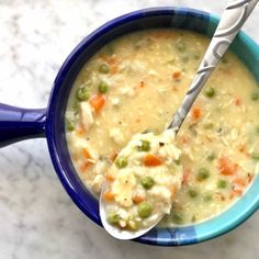 a blue bowl filled with soup on top of a white marble counter next to a spoon