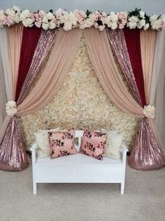 a white couch sitting under a red and pink canopy with flowers on the wall behind it