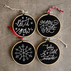 three hand embroidered christmas ornaments with words on them, hanging from twine cordes