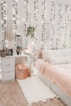 a bedroom decorated in white and pink with string lights