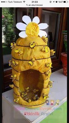 a yellow beehive with flowers and bees on it's roof is sitting in front of a window