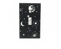 a black light switch cover with planets and stars on the front, in white background