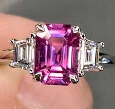 ALL THESE PHOTOS WERE TAKEN WITH AN ORDINARY IPHONE AND HAVE NOT BEEN EDITED OR ENHANCED IN ANY WAY. VIDEO LINKS: https://youtube.com/shorts/hohQex0gCL0?feature=share Up for Sale is a Gorgeous Natural Vivid Pink Sapphire & Diamond Three Stone Ring in Solid Platinum. This Ring was Made by us , Here in New York City & is of The Finest Quality. The Center Stone is a Spectacular Natural 2.6 Ct Emerald Cut Vivid Pink Sapphire that Measures approx 8.6 x 6.3 mm & was Mined in Ceylon (Sri Lanka.) It has Emerald Cut Art Deco, Wedding Rings Pink Sapphire, Diamond Ring Platinum, Pink Sapphire Diamond Ring, Ceylon Sri Lanka, Sapphire Wedding Rings, Vvs Diamond, Pink Sapphire Ring, Sapphire Wedding