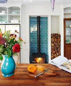 a blue vase filled with flowers sitting on top of a wooden table next to a fire place