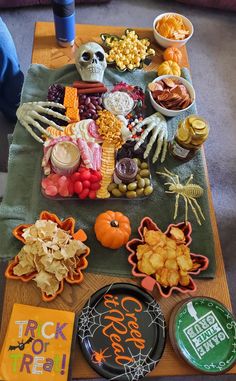 a table topped with lots of halloween food and snacks on top of a green towel