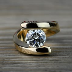 an engagement ring with a diamond in the center on a wooden surface, close up