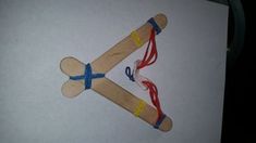 an airplane made out of wooden sticks and colored cords on a white paper sheet with scissors