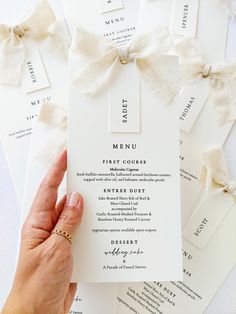 a person holding up a white menu card with bows on the front and back of it