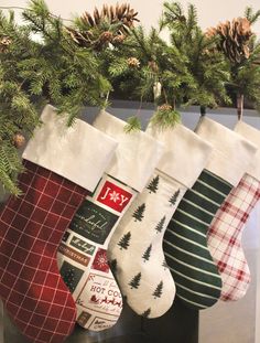 christmas stockings hanging from a mantel with pine cones