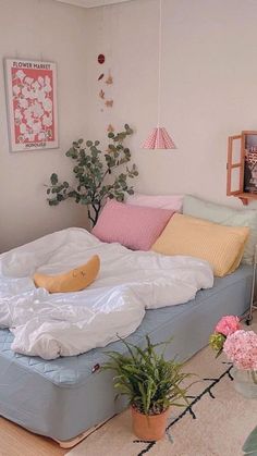 an unmade bed sitting on top of a wooden floor next to a potted plant