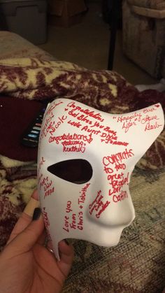 someone is holding up a white mask with red writing on it and the words written all over it