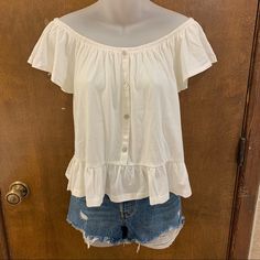 New With Tags, No Flaws. Size Medium Fits Tts But Could Really Fit Small-Medium Comfortably. Purchased From Rue21. This Cute Blouse Comes In Ivory And Features A Faux Button Front Design With Pearl-Like Buttons, Ruffle Trim Along The Hem, An Off The Shoulder Neck With A Layered Flounce Sleeve And Elastic Banding Through The Top For Easy Shoulder Placement. Material: Made From A Super Soft Cotton Blend Fabric. Slightly Stretchy And Runs A Little Thicker Than A Regular Tee While Still Maintaining Loose Shirts For Women Style, White Summer Tops With Button Closure, Casual Cream Top With Buttons, Casual Cream Buttoned Top, Casual Cream Tops For Daytime, Summer Tops With Buttons For Day Out, Cream Top With Button Closure For Day Out, Cream Tops With Button Closure For Day Out, White Top With Button Closure For Day Out