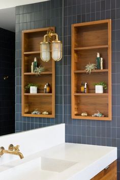 a bathroom with blue tile and wooden shelves on the wall, along with a white sink