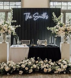 the table is set up with white flowers and greenery for an elegant wedding reception