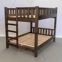 a wooden bunk bed sitting on top of a gray floor next to a white wall