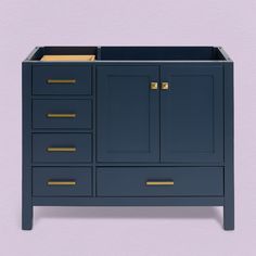 a blue bathroom vanity with gold handles and drawers on the bottom drawer, against a purple wall