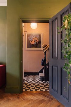 an open door leading to a hallway with green walls and wood flooring on the other side