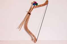 a wooden bow with two arrows and three balls on the end, attached to a white wall