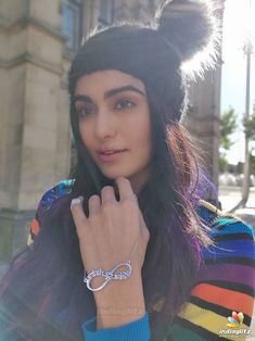 a woman with long hair wearing a colorful sweater and cat ears hat is posing for the camera