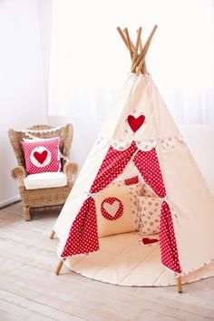 a teepee tent with hearts on it and pillows in the corner next to it