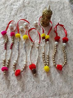 several bracelets with tassels and beads on a lace tablecloth, one has a gold buddha head