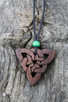 a wooden necklace with a green bead hanging from it's end on a tree trunk