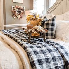 a bed with plaid blankets and pillows on top of it in a bedroom next to a window