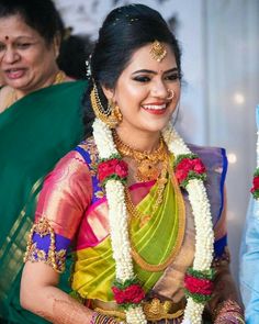 a woman in a colorful sari smiles as she stands next to another woman wearing an elaborate necklace