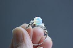 Beautiful dainty ring features a small  6 mm Opalite gemstone set in Non-tarnish silver, Sterling silver, Rose gold, Black, Copper or Gold plated wire. Opalite is a man made variety of glass. Opalite is believed to alleviate depression, soothe frayed nerves and help us to step away from anxiety. It is said to bring inner peace and a sense of calm in any situation. For this ring I have used a slightly thinner wire to make it look delicate on your finger. SIZING: All rings are made to size as sele Opalite Earrings, Opalite Jewelry, Ring Crystal, Tarnished Silver, Wire Ring, Wire Rings, Citrine Stone, Chip Beads, Stackable Ring