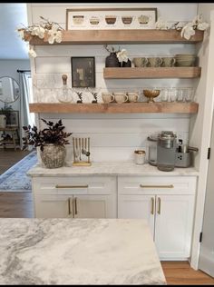 a kitchen with white cabinets and marble counter tops, gold trimmings on the shelves