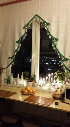 a decorated christmas tree sitting on top of a kitchen counter next to a large window