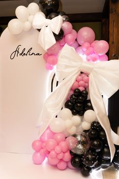 balloon arch with white bow and pink, black and white balloons in front of it