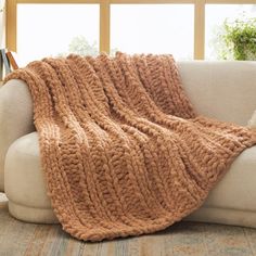 a couch with a blanket sitting on top of it next to a window in a living room