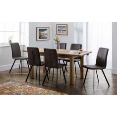 a dining room table with chairs and a rug on the floor in front of it