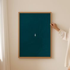 a woman pointing at a blackboard with a white object on it in front of her