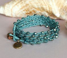 two bracelets with charms on them sitting next to a seashell