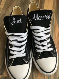 black and white sneakers with just married written on the side are sitting on a wood floor