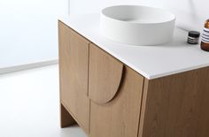 a white sink sitting on top of a counter next to a wooden cabinet with bottles