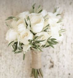 a bouquet of white roses and greenery in a vase on a wall with an ad for cell phone