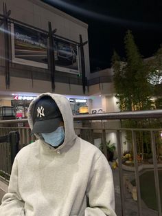 a man wearing a yankees hat and sweatshirt holding a cell phone in front of him