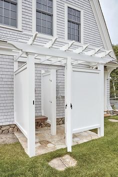 a white house with two doors and a pergolated area in the front yard