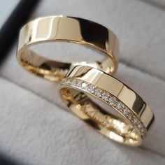 two gold wedding rings sitting on top of each other in a ring box with diamonds