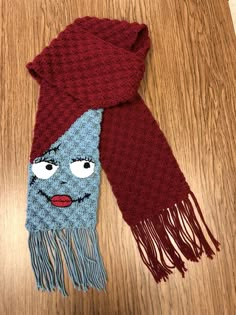 a scarf with a face on it sitting on top of a wooden floor