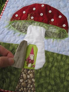 someone is holding up a piece of fabric to make a mushroom quilt on the appliance