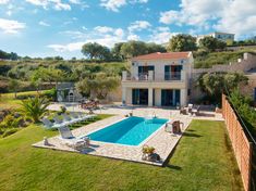 an aerial view of a house with a pool in the yard and lawn chairs around it